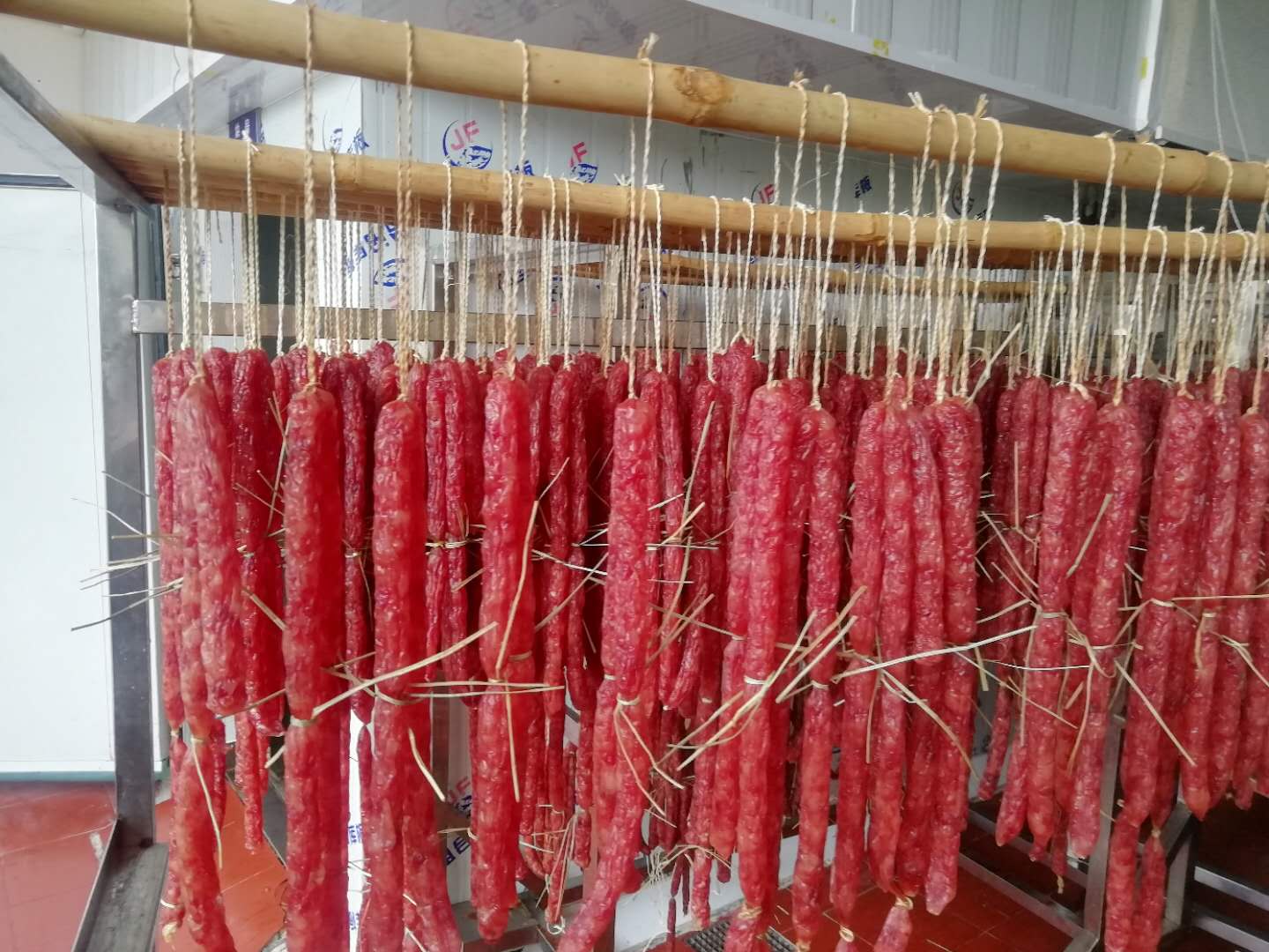腊肠灌制后用稻草手工分段,在洁净环的烘房内烘干.