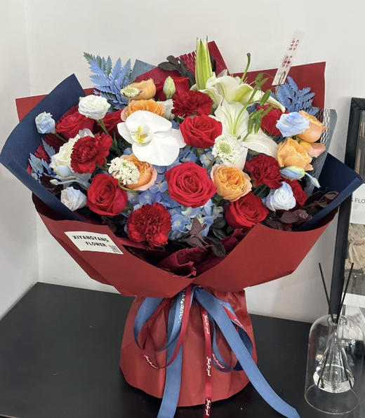 【瑞光香颂】1支海蓝色绣球➕1支白色香水百合➕1朵蝴蝶兰➕9朵红玫瑰➕6朵红色康乃馨➕6朵香槟色玫瑰➕8朵洋桔梗➕高山羊齿叶➕新鲜配花配叶，高端大气时尚花 商品图0