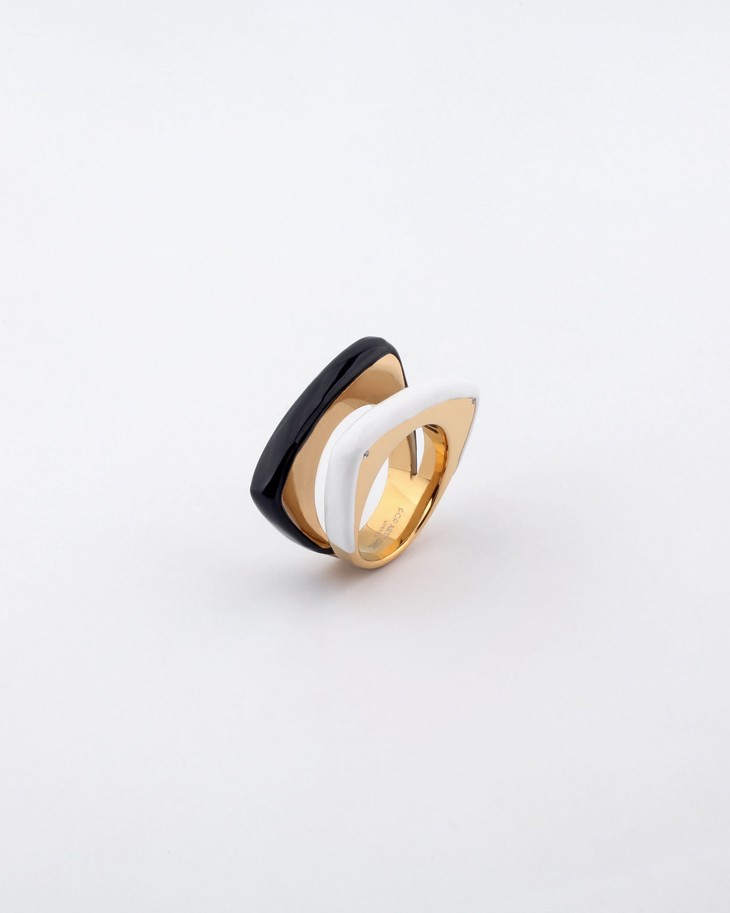 A stylish Delta Ring by For Art's Sake®, showcasing a distinctive layered design with a chic black and white contrasting color scheme. The ring exudes a modern aesthetic with its smooth, curvy shapes seamlessly blending into a polished gold base, beautifully set against a plain white backdrop.