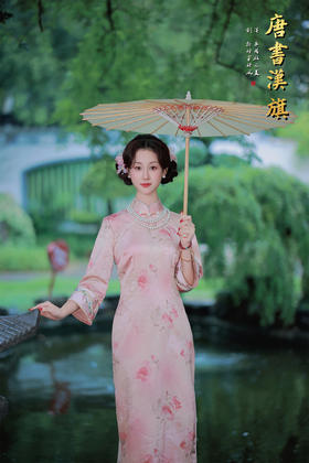 【花朝】精选柔滑缎面，淡雅粉色底衬水墨花卉，七分袖设计雅致婉约，传统立领搭配珍珠配饰更显温婉。修身剪裁勾勒东方女性柔美身姿，漫步园林时撑一柄油纸伞，尽展民国大家闺秀的古典风韵，演绎复古优雅之美。