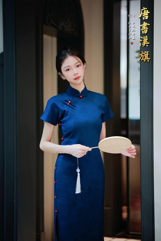 【远山黛】藏青提花旗袍高领剪裁衬出颈部线条，侧襟红珠盘扣添复古灵韵，短袖设计适配多场景穿搭；提花面料暗蕴精致纹理，修身廓形勾勒曼妙曲线，开衩细节更显步履风情。 商品图1