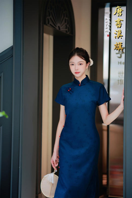 【远山黛】藏青提花旗袍高领剪裁衬出颈部线条，侧襟红珠盘扣添复古灵韵，短袖设计适配多场景穿搭；提花面料暗蕴精致纹理，修身廓形勾勒曼妙曲线，开衩细节更显步履风情。 商品图2