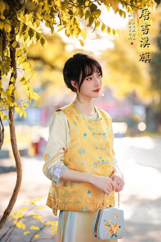 【凌霄（醋酸提花）】衣身以明黄为底，满幅暗织蓝调花蝶提花纹理，古典雅致；门襟缀青蓝盘扣，细节处尽显中式巧思，短款版型适配多元内搭，可叠穿衬衣、高领衫打造层次。 商品图5