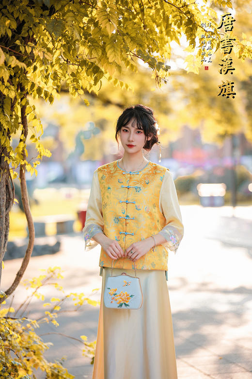 【凌霄（醋酸提花）】衣身以明黄为底，满幅暗织蓝调花蝶提花纹理，古典雅致；门襟缀青蓝盘扣，细节处尽显中式巧思，短款版型适配多元内搭，可叠穿衬衣、高领衫打造层次。 商品图0