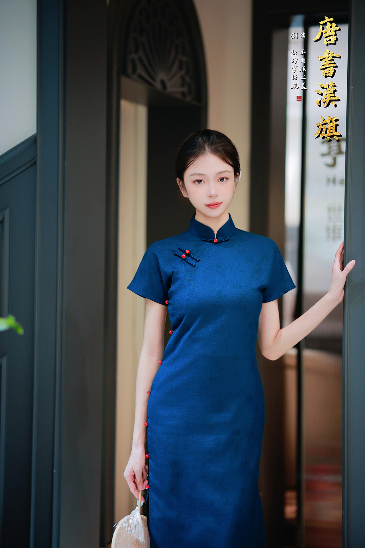 【远山黛】藏青提花旗袍高领剪裁衬出颈部线条，侧襟红珠盘扣添复古灵韵，短袖设计适配多场景穿搭；提花面料暗蕴精致纹理，修身廓形勾勒曼妙曲线，开衩细节更显步履风情。