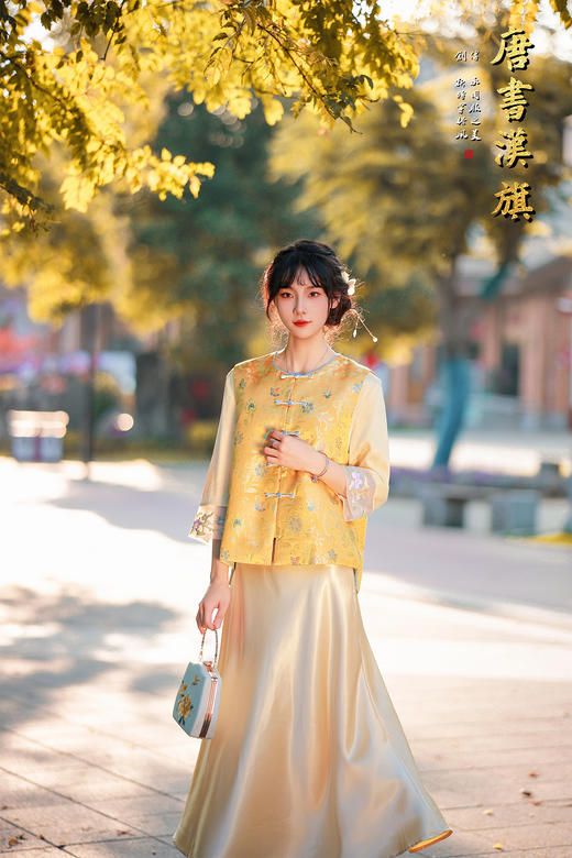 【凌霄（醋酸提花）】衣身以明黄为底，满幅暗织蓝调花蝶提花纹理，古典雅致；门襟缀青蓝盘扣，细节处尽显中式巧思，短款版型适配多元内搭，可叠穿衬衣、高领衫打造层次。 商品图1
