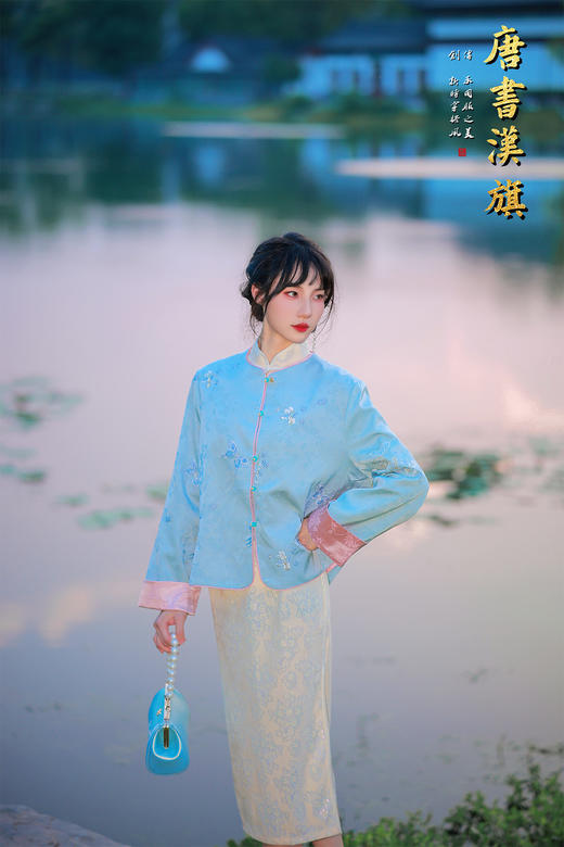 【粉蓝织梦】水蓝刺绣中式短衫，融江南水韵于衣袂之间。   衣身以清透水蓝为底，暗织雅致提花并点缀精巧刺绣，领口与袖口饰柔粉滚边，细节处尽显国风温婉；立领设计衬出颈部线条 商品图1