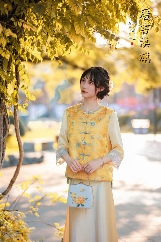 【凌霄（醋酸提花）】衣身以明黄为底，满幅暗织蓝调花蝶提花纹理，古典雅致；门襟缀青蓝盘扣，细节处尽显中式巧思，短款版型适配多元内搭，可叠穿衬衣、高领衫打造层次。 商品图6